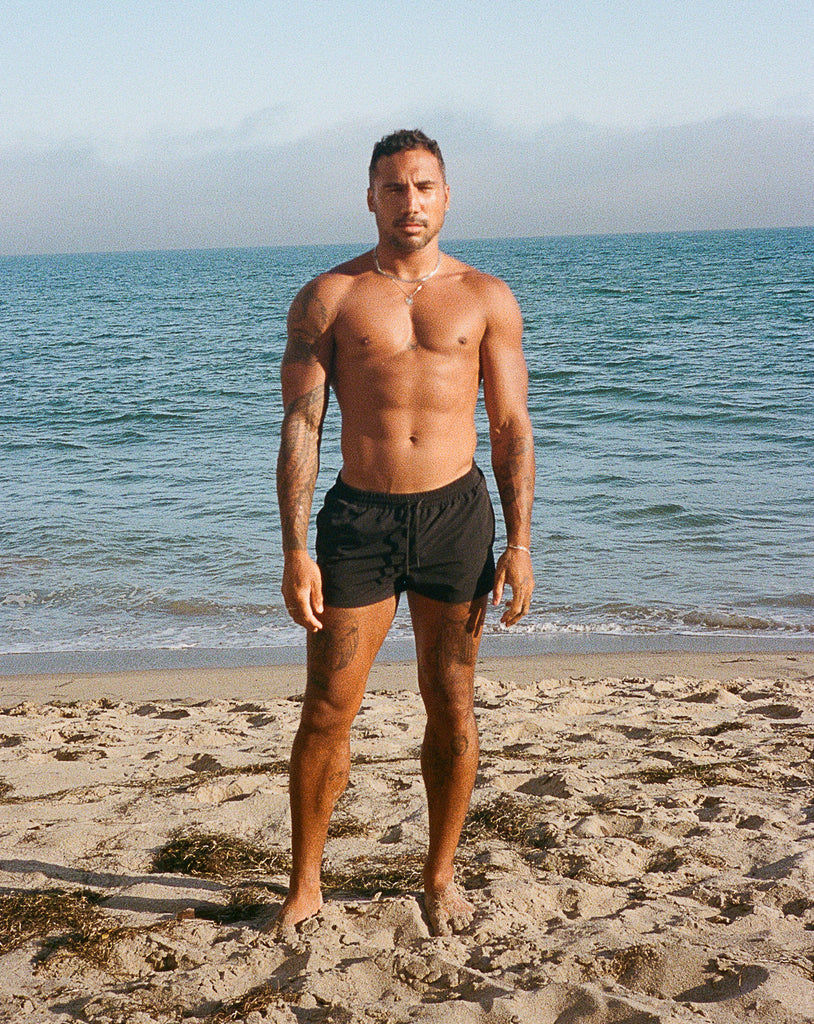 Model in black swim short on beach