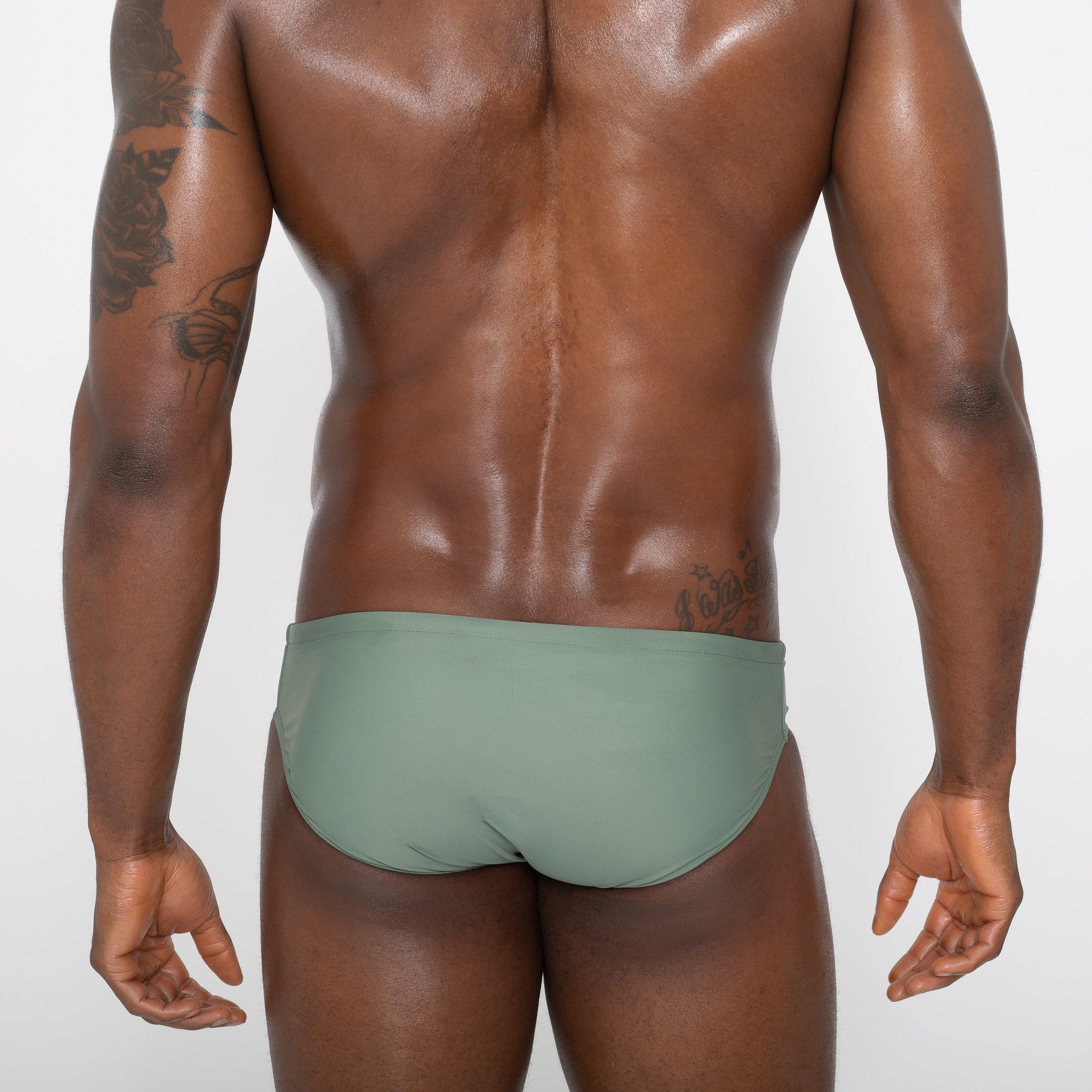 Man wearing light green swim brief. Back view.